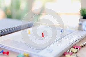 Close-up red pin on blank desk calendar with office equipment concept of event planner or personal organization for