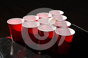 close up red plastic beer pong cups with white ball on top of beer pong set up