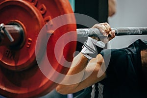 close-up red plates barbell and arm female powerlifter