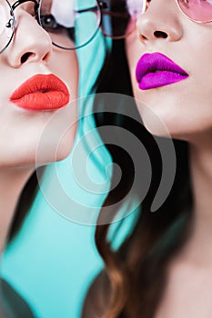 Close up of red and purple lips of two women on blue background. Cosmetics, makeup, lipstick, lip gloss