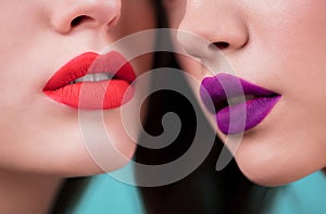 Close up of red and purple lips of two women. Cosmetics, makeup, lipstick, lip gloss, facial care.