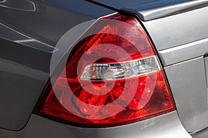 Close-up of a red rear brake light replaced after an accident on a white car in the back of a sedan after washing and cleaning for