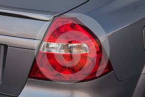 Close-up of a red rear brake light replaced after an accident on a white car in the back of a sedan after washing and cleaning for