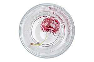 Close up the red ripe cherry in soda water with bubbles of carbon dioxide on white background.