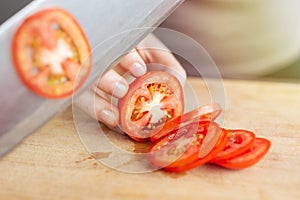 Close up of red ripe tomato cutting with a knife. Healthy food preparation concept