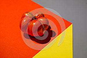 Close up of ugly red ripe tomato on abstract paper background.