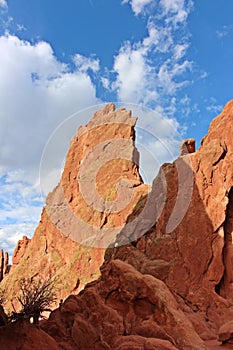 Close up of red rock pinnacles rising up against a blue sky with fluffy white clouds at the Garden of the Gods in Colorado
