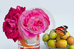 Close up of red roses in a glass and butterfly on jujuba  zizyphus  fruits