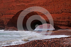 Close-up of red sandstone stone arch in Legzira Beach. Rugged coastline in Tiznit Province of Morocco, Africa. Atlantic Ocean.