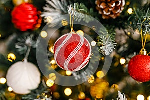 A close-up of red and silver glittering ornaments on a branch of a Christmas tree