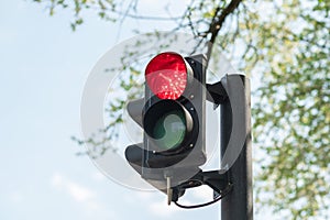Close-up of red traffic light for cars with a blue sky in the background.