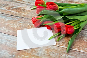 Close up of red tulips and blank paper or letter