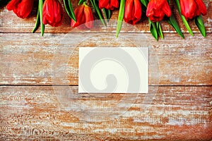 Close up of red tulips and blank paper or letter