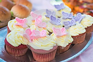 Close-up of red velet cupcakes with white cream cheese on top decorated with colorful butterflies. Catering for burthday