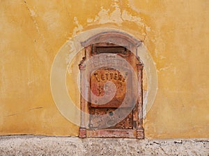 Close up of red vintage letter box against yellow wall.