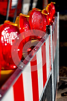 Close-up of red warning lights with street barriers blurry foreground and background