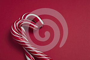 Close-up of red and white candy canes on a red surface with space for text