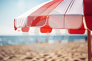 Close up of red and white striped sun parasol with blurry beach in background