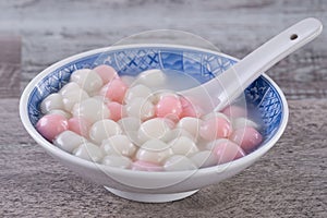 Close up of red and white tangyuan in blue bowl on wooden background for Winter solstice photo