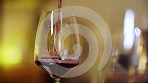Close up red wine poured into glass in bar