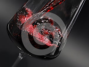 close up of red wine pouring in a glass isolated on black background
