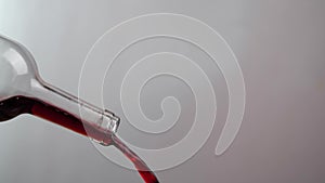 a close-up of red wine pouring out of a glass bottle. Wine bottle isolated