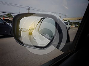 Close up reflection blurred roadway view on side mirror car during driving car on the way.  sunset taken by car side mirror.