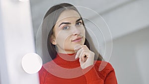 Close-up reflection of charming slim beautiful brunette woman with brown eyes looking at camera through mirror. Portrait