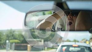 CLOSE UP: Reflection of frustrated young man yelling at car in front of him.