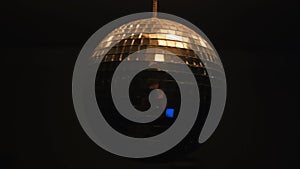 Close up of reflective disco ball isolated on black background. Concept. Rotating golden shining disco ball in the dark