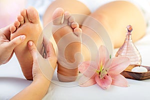 Close up of reflexologist massaging female feet with aromatic oil in spa.