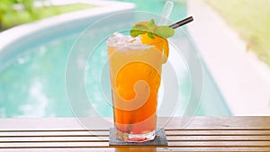 Close up of a refreshing orange drink with straw and mint leaf