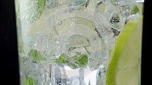 Close-up refreshing soda tonic. Pour carbonated water into a glass of lime and ice. Cold Mojito lemonade