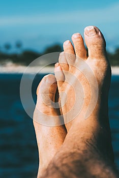 Close-Up of a Relaxing Barefoot With Toes Up Against a Sunny Beach Background and flip flop tan marks