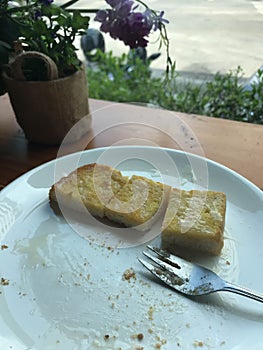 Close up remaining of sliced toasted bread with butter and sweetened condensed milk on white dish after full