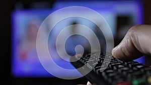 Close-up of a remote control held by a man while changing channels compulsively