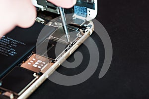 Close-up with the repair of a used smartphone with a screwdriver