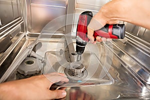 Close-up Of Repairman Fixing Dishwasher