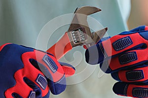 Close up of repairman hands in gloves holding wrench.