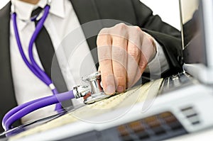 Close up of repairman holding stethoscope of laptop keyboard