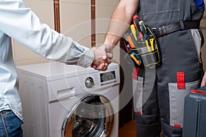 Close-up of a repairman shaking hands with a female customer. Male repairman for washing machine repair