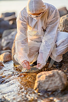 Close-up of researcher collecting water sample at seashore