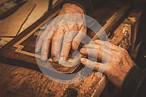 Close-up of restorer hands working with antique decor element in his workshop