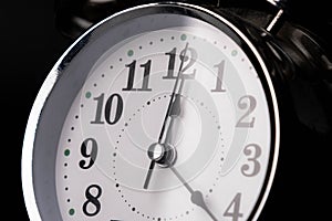Close-up of a retro alarm clock face on a black background. Clock hands move fast, the beginning of time 12:00 AM or 12:00 PM