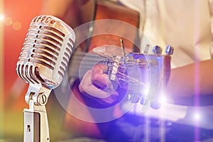 Close up retro microphone with musician playing acoustic guitar on band