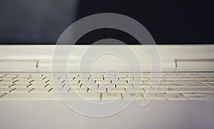 Close up of retro white laptop keyboard. Old computer background, keypad pattern texture and black screen