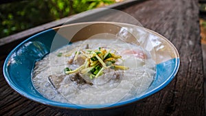 Close up Rice porridge ,congee with minced pork and ginger in white and blue bowl,Rice soup concept, on the table