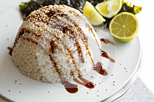 Close-up, rice topped with sauce and sprinkled with sesame seeds.