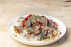 Close-up Rice topped with stir-fried beef and holy basil on the wooden table, popular Thai street food