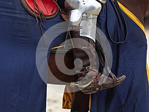Close-up of the rider& x27;s leg in historical armor on a horse. Shoes with a long nose, stirrups.
